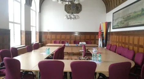 Bild zeigt einen leeren Sitzungssaal in einem Rathaus